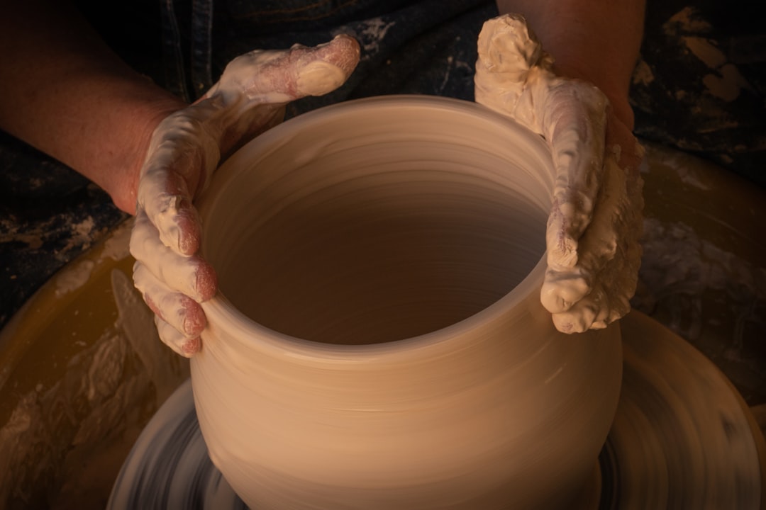 Hands shaping a clay vessel.